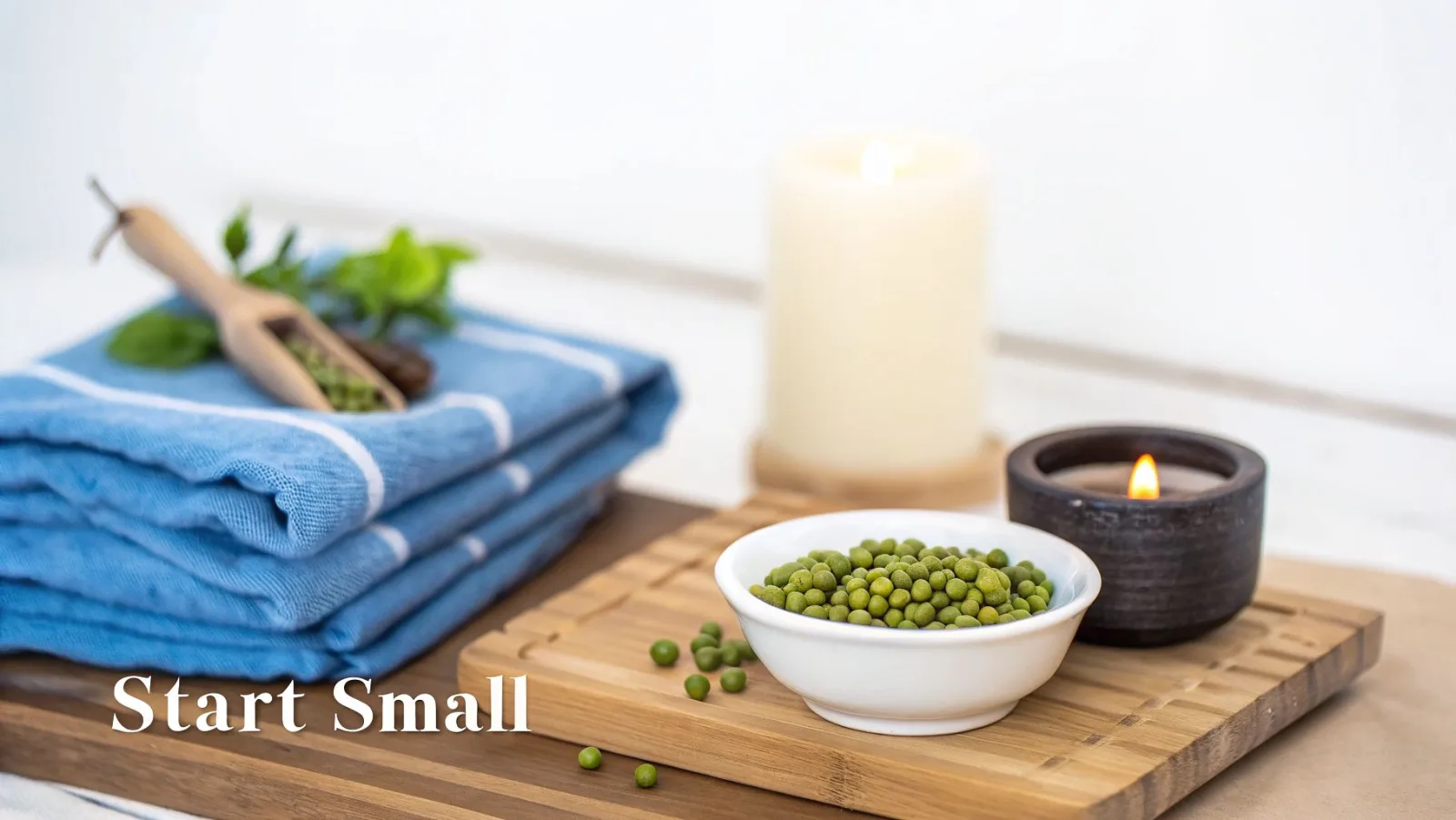 Ein beruhigendes Wellness-Arrangement mit blauen Handtüchern, einem Holzlöffel mit grünen Erbsen und brennenden Kerzen auf einem Bambustablett.