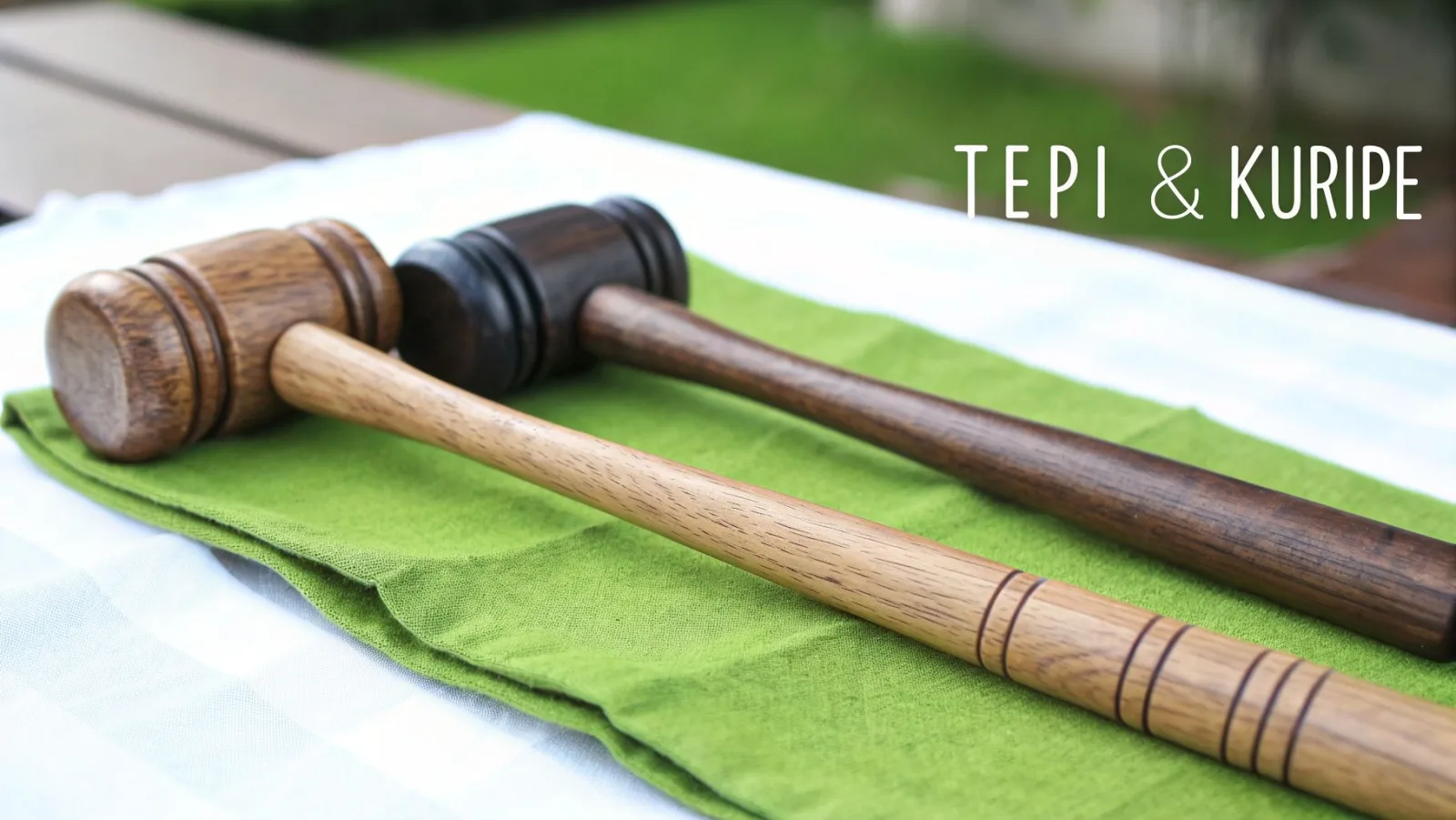 Zwei handgefertigte Tepi- und Kuripe-Werkzeuge aus Holz, eines hell und eines dunkel, auf einem grünen Tuch.