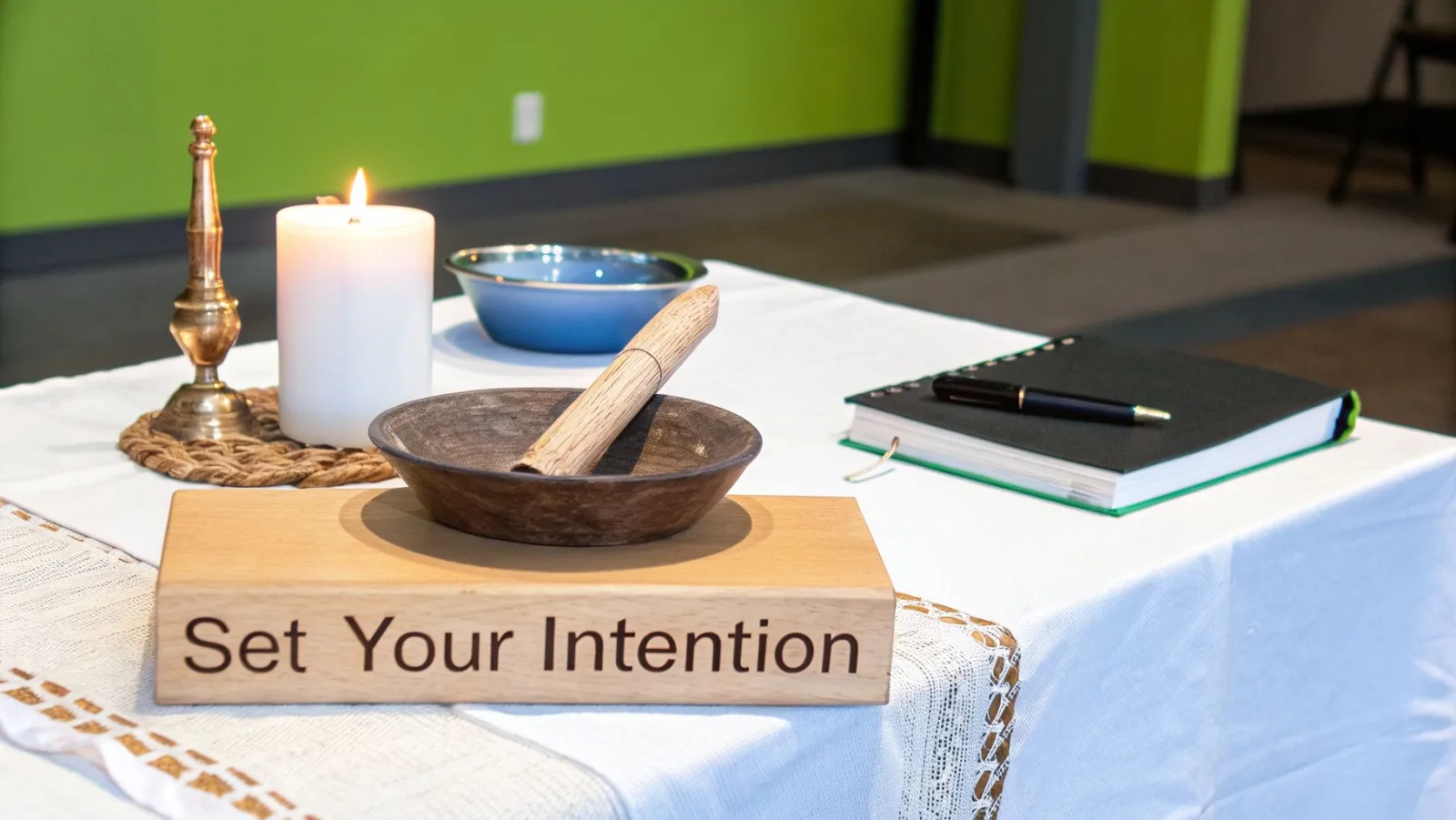 Ein ruhig gestalteter Tisch mit einer brennenden Kerze, Meditationsschalen, einem Notizbuch und einem Schild mit der Aufschrift „Set Your Intention“.