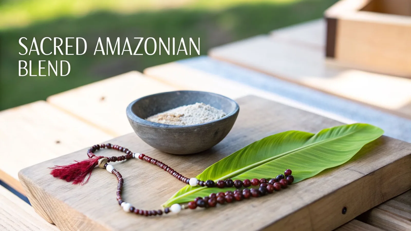 Ein heiliges Pulver aus dem Amazonas in einer Steinschale mit Gebetsperlen und einem grünen Blatt auf einer Holzoberfläche.